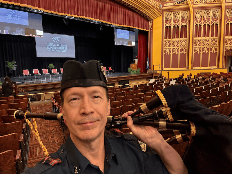 Kendall Giles holding bagpipes inside Burruss Hall at Virginia Tech